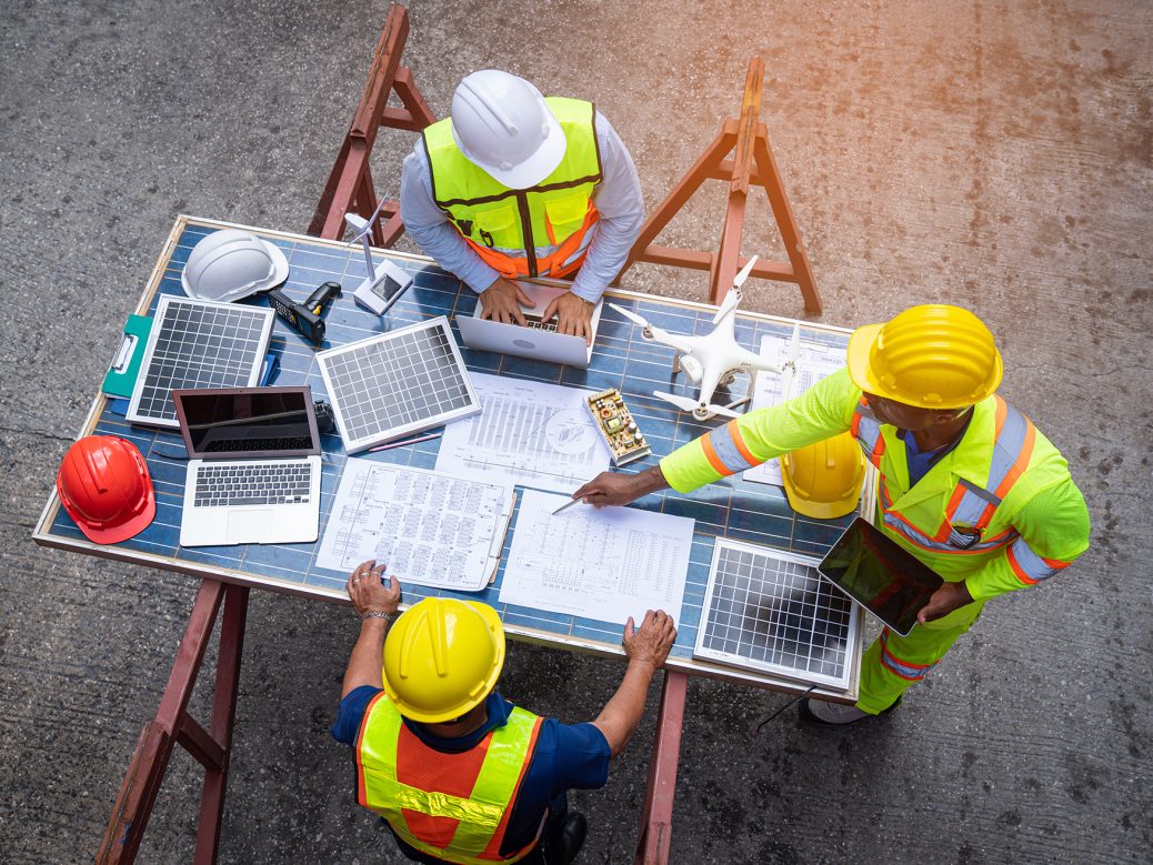 Engineers in team discussion on site, solar panels
