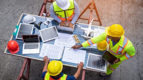 Engineers in team discussion on site, solar panels